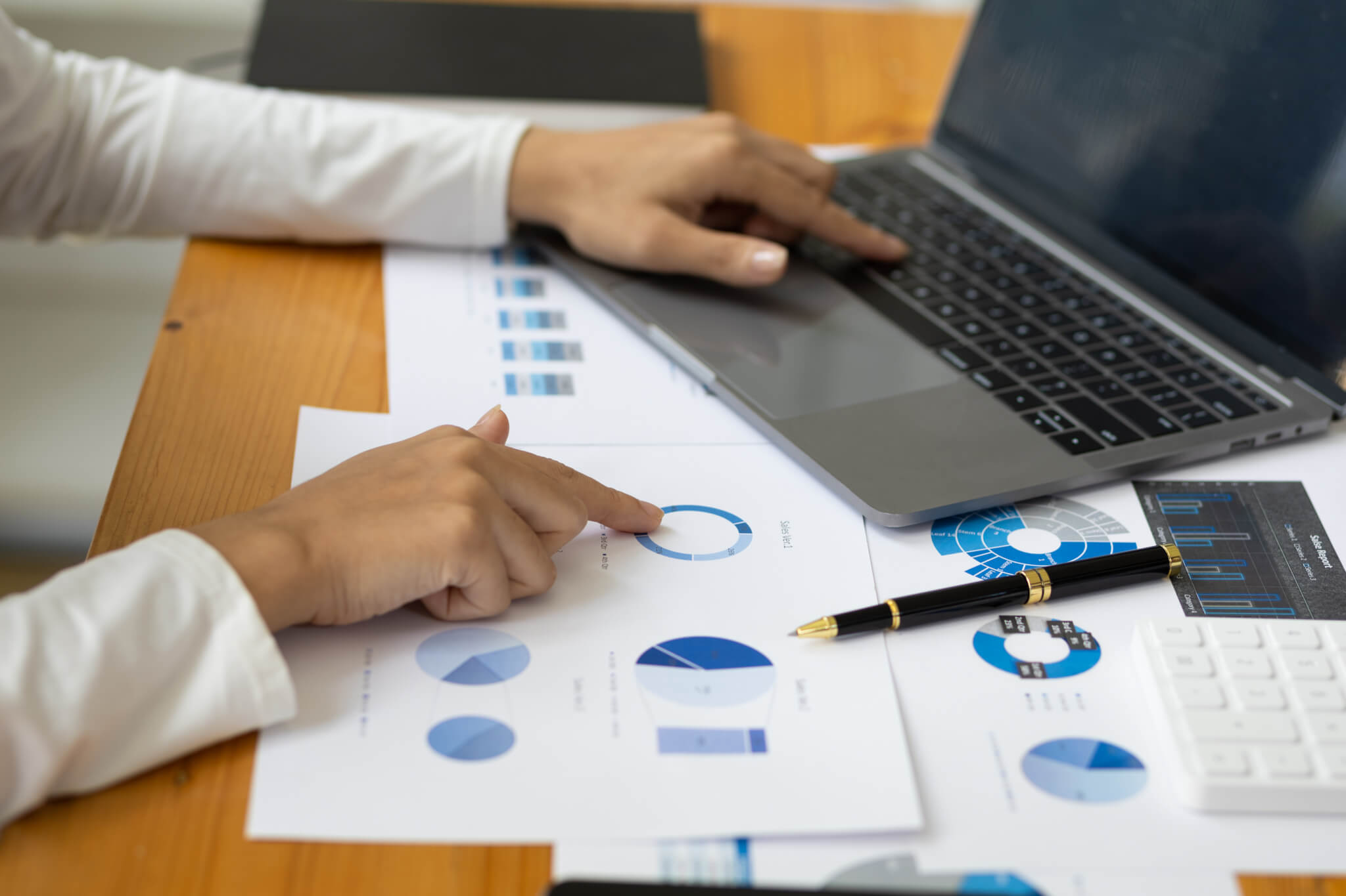 Woman analyzing business reports and investment data on laptop.